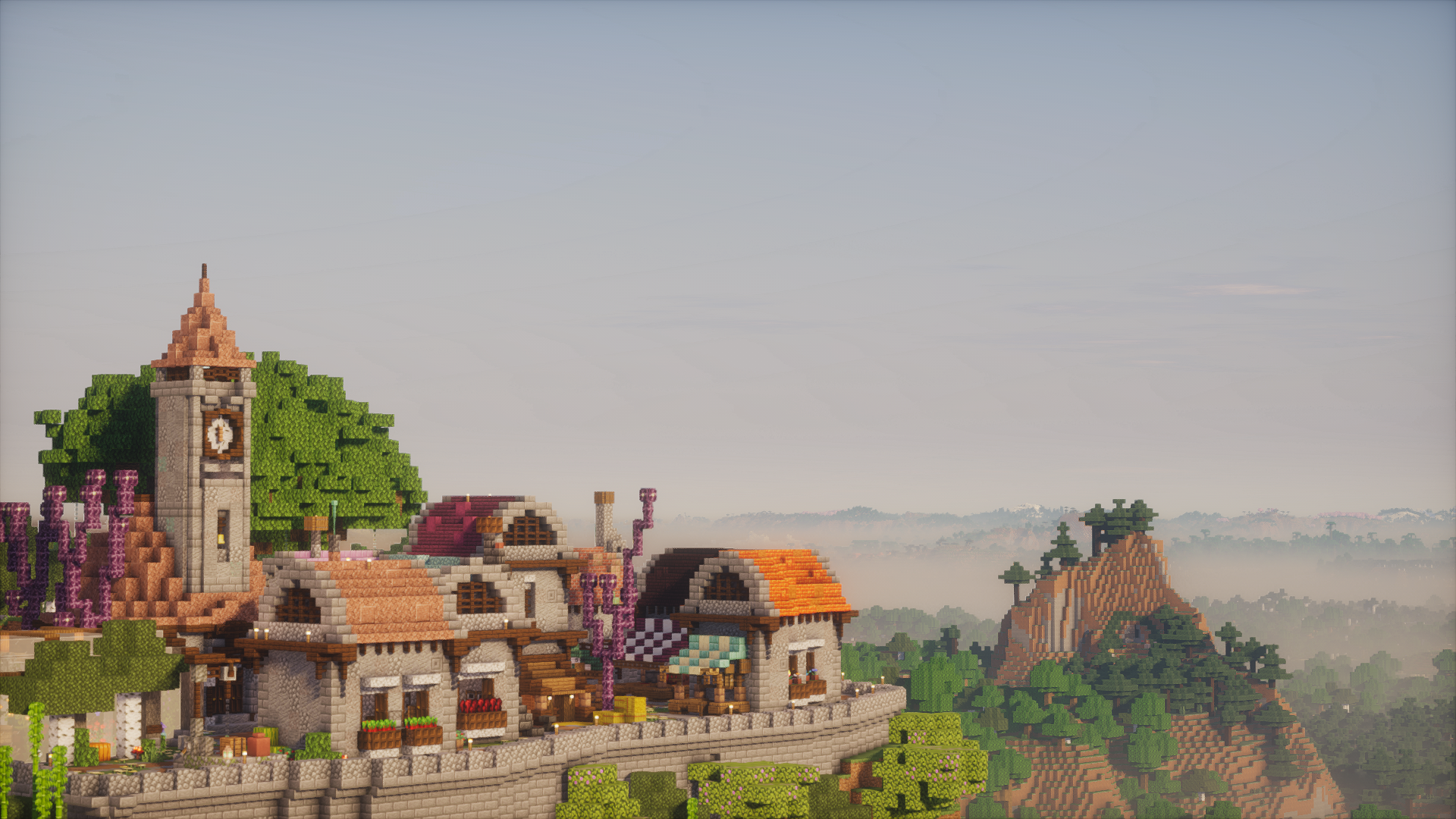 A bright village and clock tower perched above a forested valley