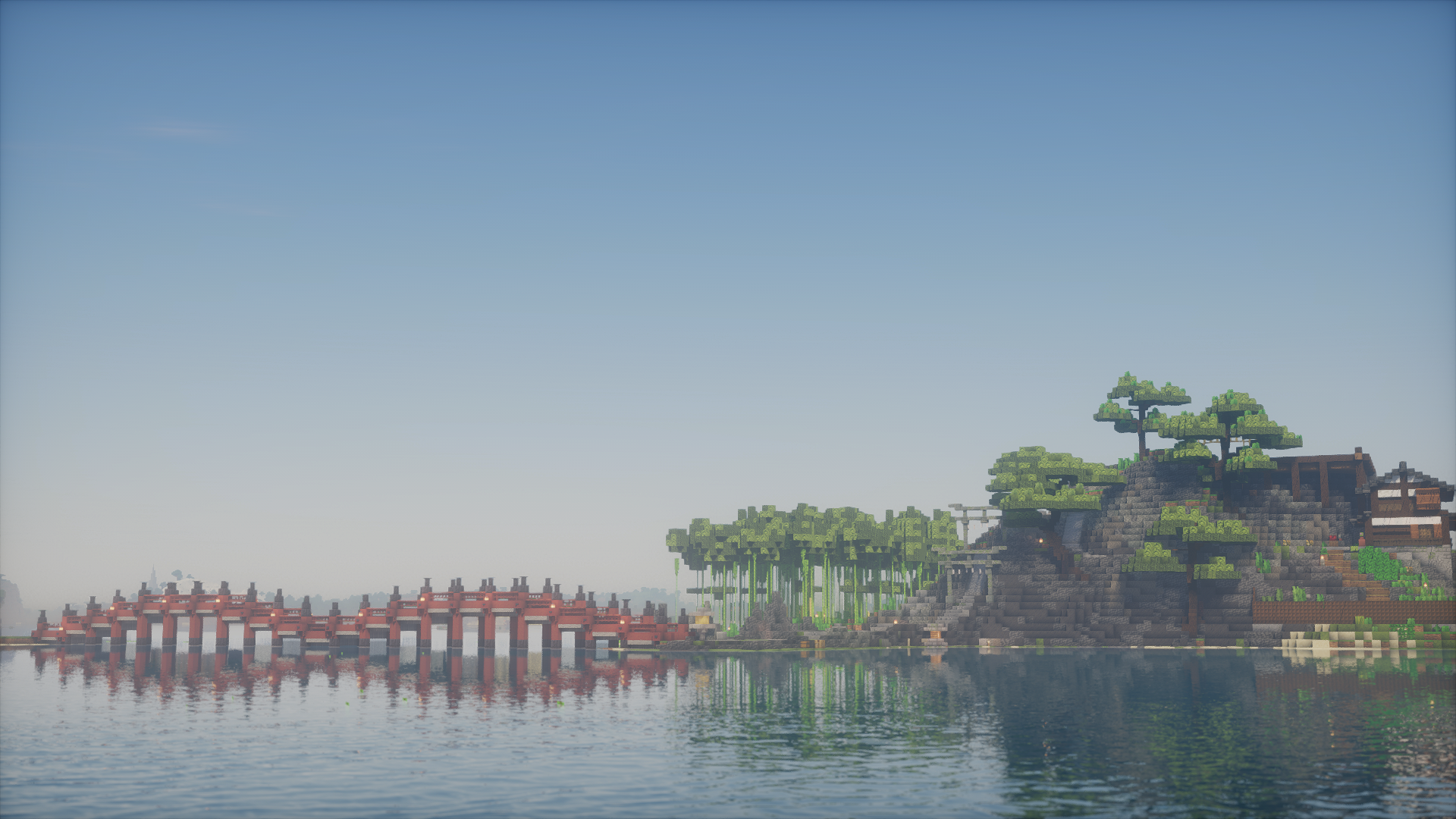 A long red bridge reaching toward a bamboo-covered hill